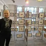 Barbara Hammes, Hugendubel, steht vor Scherenschnitten von Achim Rippberger