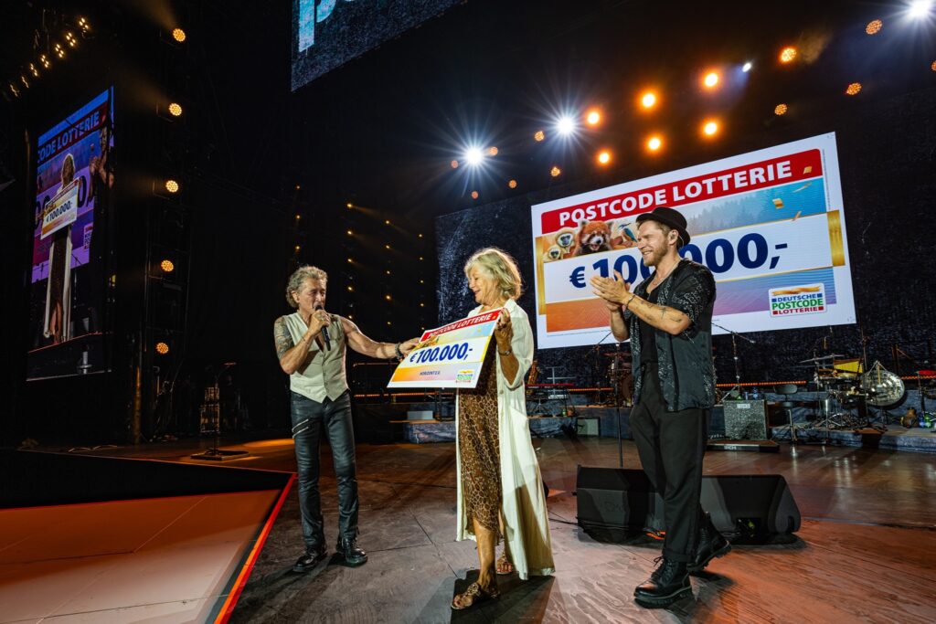 1,1 Millionen Euro für den guten Zweck: Peter Maffay überrascht bei Farewell Tour elf Organisationen 1 Diese Überraschung in München ist gelungen: Peter Maffay (links) überreicht Schauspielerin und Horizont-Gründerin Jutta Speidel zusammen mit Musiker Johannes Oerding einen Scheck über 100.000 Euro. Bildrechte:Ralph Larmann Fotograf: Deutsche Postcode Lotterie