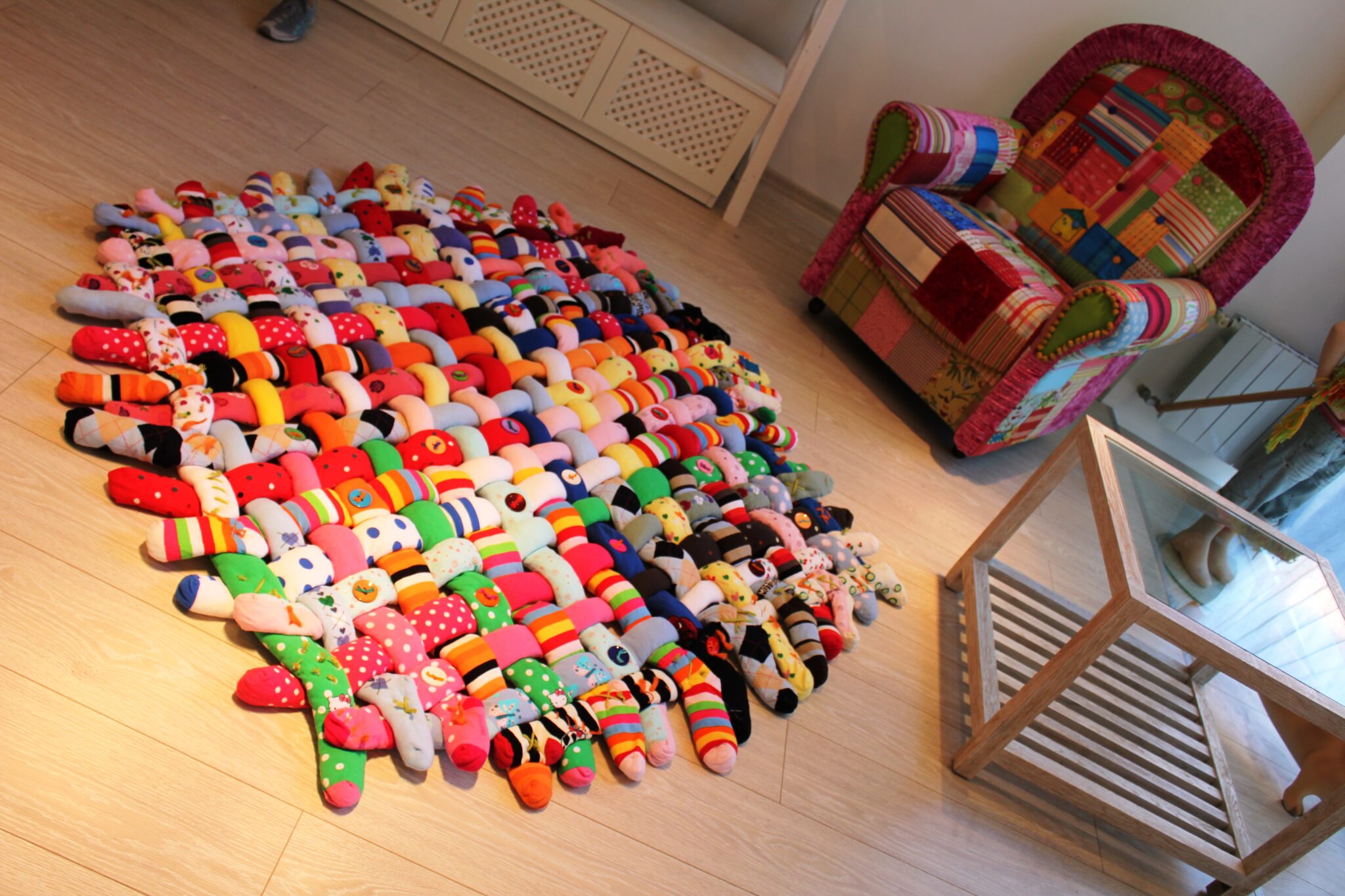 Design mit Persönlichkeit: Vlada Dizik und Aleksandr Myalkovskyy verbinden Interior Design, Nachhaltigkeit und Kreativität zu außergewöhnlichen Wohnkonzepten. Der handgefertigte Teppich aus recycelten Socken steht exemplarisch für ihre innovative Designphilosophie.