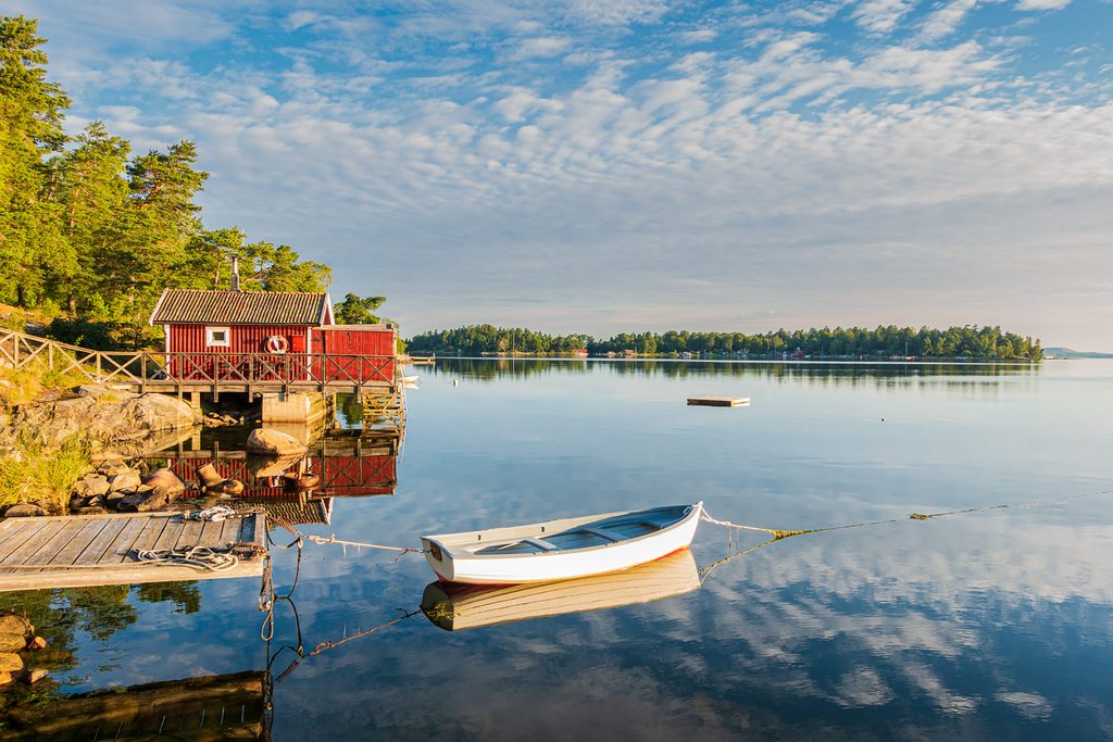 IKARUS TOURS: Neue Fernreisen und Europareisen 2027 3 Skandinavische Idylle in Schweden: Traditionelles rotes Holzhaus, Boot und spiegelglattes Wasser stehen für die faszinierende Natur Nordeuropas. Mit IKARUS TOURS lassen sich Schwedens Landschaften auf ausgewählten Erlebnis- und Studienreisen entdecken. Bild: © iStock / IKARUS TOURS
